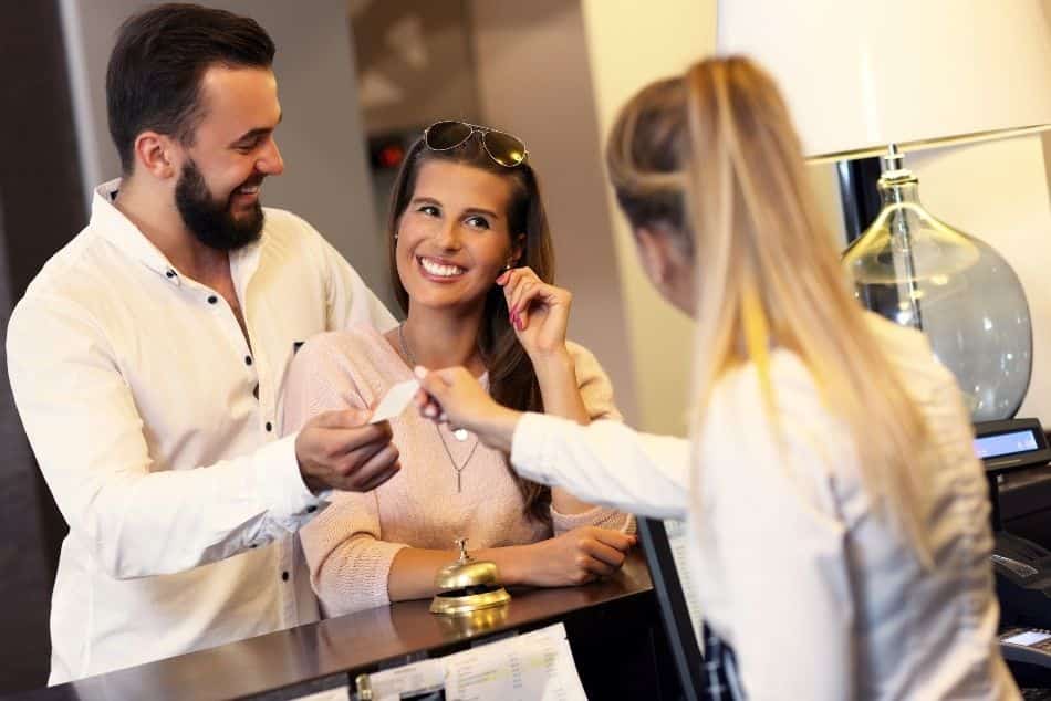 picture-couple-receptionist-counter-hotel-smiling-giving-card